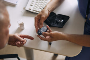 Doctor measuring blood sugar of patient at desk in medical clinic